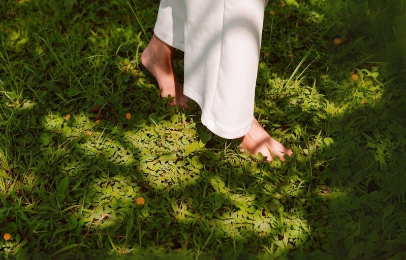 Bare feet walking on a sunlit grassy path